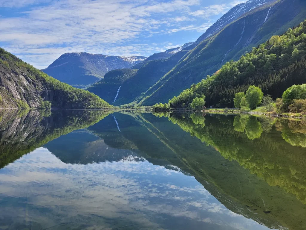 Horizontal view of the peaceful water surface of Eidsvatnet lake with soft ripples and distant green hills.