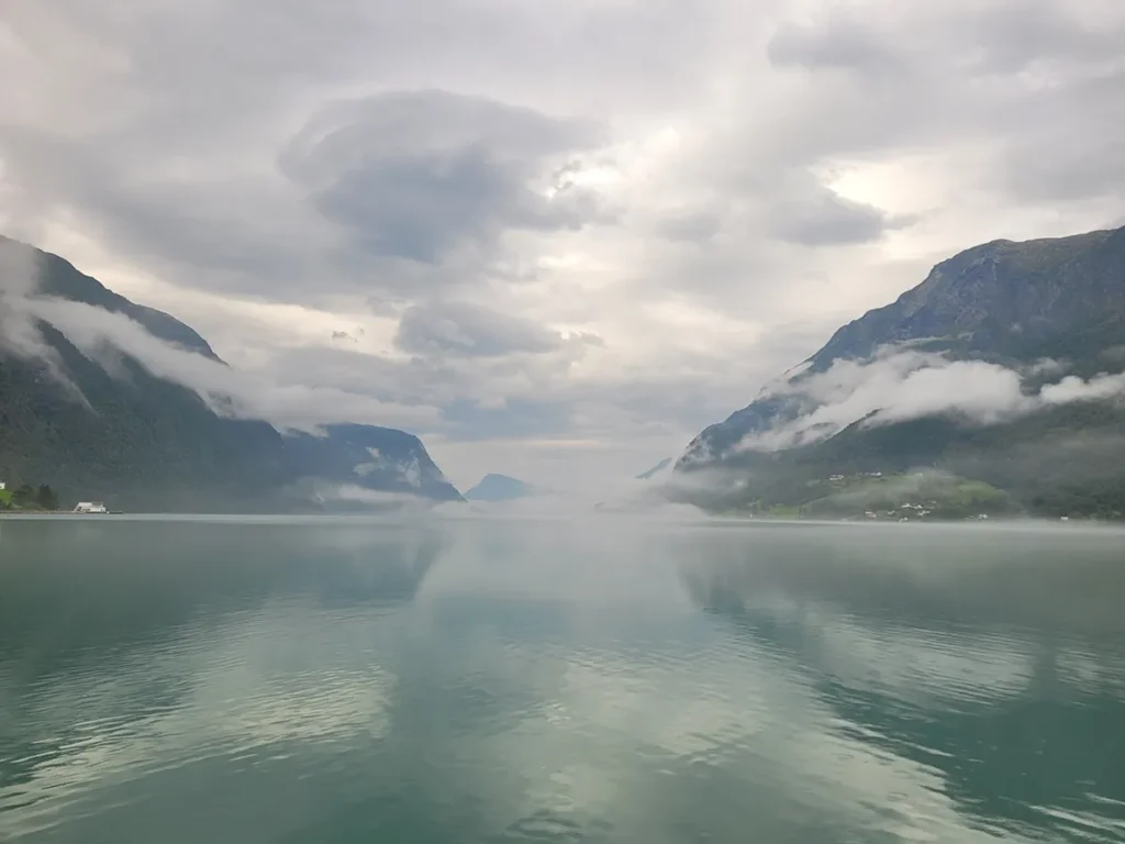 Breathtaking summer scenery of the calm waters of Lustrafjorden reflecting green mountainsides in Norway.